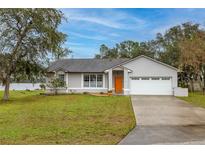 Charming home featuring a well-manicured lawn, attached garage, and freshly painted exterior at 1983 Stacey Cir, Deltona, FL 32738