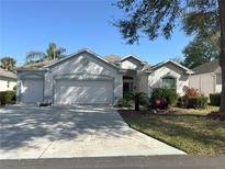 Charming single-story home with a well-manicured lawn, two-car garage, and lovely landscaping under a clear blue sky at 2327 Addison Ave, Clermont, FL 34711