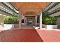 Inviting condominium entrance with covered entryway and red brick drive, framed by lush greenery at 2967 S Atlantic Ave # 1203, Daytona Beach Shores, FL 32118