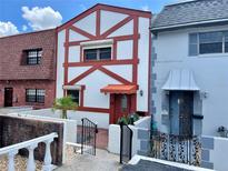 Charming two-story townhome featuring a white and red Tudor-style facade with well-maintained landscaping and a gated entrance at 625 N Halifax Ave # 15, Daytona Beach, FL 32118