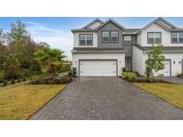 Charming two-story townhome featuring a paved driveway, two-car garage, and well-maintained landscaping at 1401 Brookdale Ct, Oviedo, FL 32765