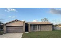 Single-story home featuring a large attached garage, brick facade, and manicured lawn at 1420 Felton St, Deltona, FL 32725