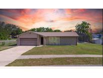 Charming single-story home with an attached garage, well-kept lawn and colorful sunset backdrop at 1420 Felton St, Deltona, FL 32725