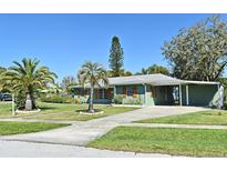 Charming single-story home with green paint, lovely shutters, carport, manicured lawn, and tropical landscaping at 1590 N Page Dr, Deltona, FL 32725