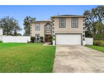 Two-story home featuring an attached two-car garage, a well-manicured lawn, and a neatly landscaped garden bed near the front entrance at 3318 Dewberry Dr, Deltona, FL 32738