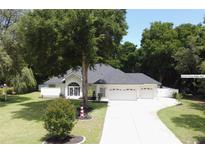 Charming single-story home with well-manicured lawn, mature trees, and a long driveway leading to a three-car garage at 36320 Piney Ridge Blvd, Fruitland Park, FL 34731