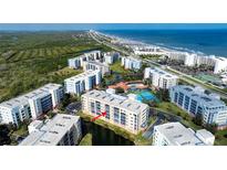 Stunning aerial view of beachfront condo complex with pool, tennis courts, and ocean views at 5300 S Atlantic Ave # 8-404, New Smyrna Beach, FL 32169