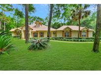 Beautiful one-story home with a lush lawn, mature trees, and manicured landscaping at 1875 Glenwood Oaks Ln, Deland, FL 32720