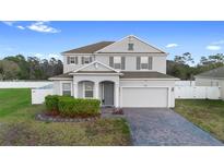 Charming two-story home with landscaped yard, brick driveway, and attached two-car garage at 3565 Fernanda Dr, Deltona, FL 32738