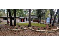 Charming single-story home with a landscaped front yard featuring a colorful door and mature trees at 165 Franklin Rd, Lake Mary, FL 32746