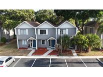Two-story townhome with gray siding, white trim, a brown roof, well-manicured landscaping, and ample parking at 3960 Willow Trail Run # 45, Port Orange, FL 32127