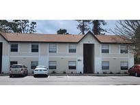 Exterior of a two-story condo building with neutral paint, brown roof, and ample parking at 411 Banana Cay Dr # C, South Daytona, FL 32119