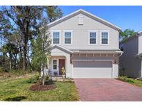 Charming two-story home with a red brick driveway and well-manicured lawn and attached garage at 1088 Happy Forest Loop, Deland, FL 32720