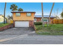 Two-story home featuring a front yard, two-car garage, and a durable metal roof at 1493 Derbyshire Rd, Daytona Beach, FL 32117