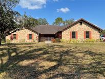 Charming brick home with a well-manicured lawn, colorful foliage, and a lovely, inviting facade at 1990 Spruce Creek N Cir, Port Orange, FL 32128