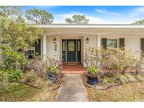 Inviting front entrance with black door, decorative plants, and a brick-paved walkway at 28 W Highbanks Rd, Debary, FL 32713