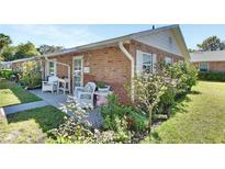 Charming brick home featuring a cozy front porch with white wicker furniture and a beautifully landscaped garden at 37 Fairway Ct # C, Deland, FL 32724