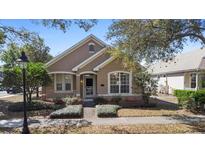 Charming tan home featuring a manicured front yard with beautiful landscaping and a pathway to the front door at 406 Ravenshill Way, Deland, FL 32724