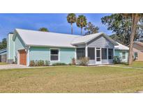 Charming single-story home features a metal roof, screened-in porch, garage and fresh green lawn at 437 Merrimac Dr, Port Orange, FL 32127