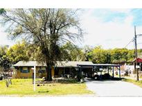 Charming one-story home featuring a spacious front yard with mature trees and a covered carport at 5076 Fairport Ave, De Leon Springs, FL 32130