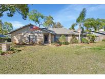 Charming single-story brick home featuring a well-manicured lawn, front flower beds and an American flag at 725 Briarcrest Dr, Orange City, FL 32763