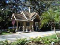 Charming gated entrance with stone accents, a tiled roof, and lush landscaping at 123 Tomoka Trl # 123, Longwood, FL 32779