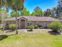 Charming brick home featuring lush landscaping, mature trees, and a welcoming front entrance at 1490 Kettledrum Trl, Enterprise, FL 32725
