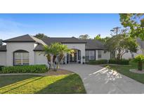 Beautiful single-story home features a white painted brick exterior, black trim, landscaping, and a curved driveway at 1540 Park Forest Blvd, Mount Dora, FL 32757