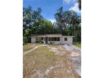 Charming single-story home with a screen door entry and a lush, wooded front yard at 318 S Massachusetts Ave, Deland, FL 32724