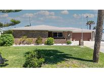 Charming brick home featuring a manicured front lawn and beautifully landscaped garden beds with white rock at 7 Kathy Dr, Ormond Beach, FL 32176