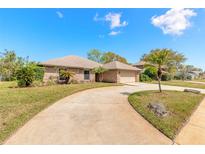 Charming brick home with well-maintained landscaping and a spacious driveway, under a beautiful blue sky at 811 Smokerise Blvd, Port Orange, FL 32127