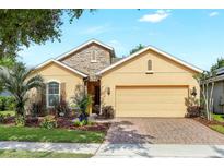 Inviting single-story home with a well-manicured lawn, stone accents, and a two-car garage at 1386 Hazeldene Mnr, Deland, FL 32724