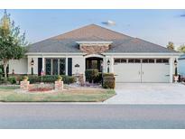 Charming home featuring a stone facade, manicured lawn, and a two-car garage at 1606 Tango St, The Villages, FL 32163