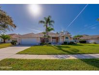 Inviting single-story home boasts lush landscaping, mature palms, and a two-car garage at 1792 Arash Cir, Port Orange, FL 32128