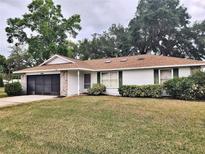 Charming single-story home with mature trees, manicured lawn, and attached two car garage at 1167 Peachtree Rd, Daytona Beach, FL 32114