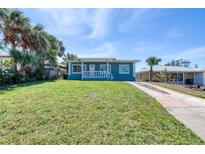 Charming single-story home with a well-manicured lawn, complemented by mature palm trees and a cozy front porch at 130 Harrison Rd, Daytona Beach, FL 32118