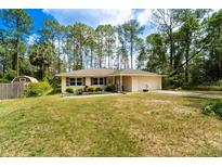 Charming single story home with a manicured lawn, mature landscaping and a two car garage in a wooded setting at 2309 6Th Ave, Deland, FL 32724
