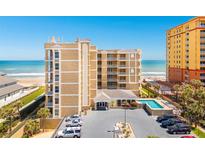 Beautiful condo building exterior with tan siding, ocean view, and outdoor pool at 2855 S Atlantic Ave # 303, Daytona Beach Shores, FL 32118