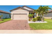 Charming single-story home featuring a brick driveway, two-car garage, and tropical landscaping at 3128 Crab Trap Dr, New Smyrna Beach, FL 32168