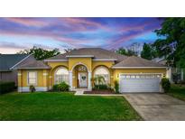Charming, yellow single-story home featuring arched windows, a well-maintained lawn, and a two-car garage at 316 Oak Springs Dr, Debary, FL 32713