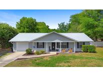 Charming single-story home with a new silver metal roof, inviting front porch, manicured lawn and mature landscaping at 4836 Ne 26Th Ter, Ocala, FL 34479