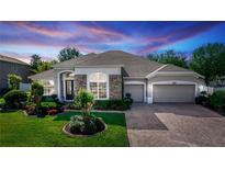 Charming single-story home boasts stone accents, manicured lawn, and a three-car garage at 4901 Lake Milly Dr, Orlando, FL 32839