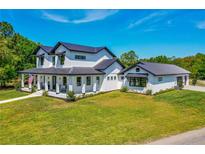 Beautifully landscaped two-story modern farmhouse with black metal roof and inviting front porch at 1015 Tallacoe Trl, New Smyrna Beach, FL 32168