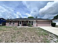 Charming single-story brick home featuring an attached garage and a well-maintained front yard at 1054 Abeline Dr, Deltona, FL 32725