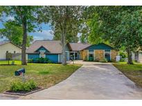 Charming blue home with stone accents, mature trees, and a long driveway creating curb appeal at 1206 Parkside Dr, Ormond Beach, FL 32174