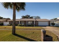 Charming brick home with a well-manicured lawn, mature palm tree, and inviting curb appeal at 18 Buckingham Dr, Ormond Beach, FL 32176
