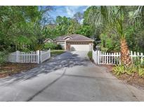 Charming single-story brick home with a well-manicured lawn and a white picket fence lined driveway at 1925 Hamilton Ave, Orange City, FL 32763