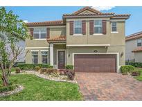 Two-story home featuring a red-tiled roof, brown shutters, a two-car garage, and a brick driveway with landscaping at 199 Verde Way, Debary, FL 32713