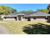 Charming brick home featuring solar panels, a well-maintained lawn, and a welcoming entrance at 2053 Bond Rd, Deland, FL 32720