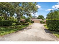 Charming home with a large front yard, mature trees, lush landscaping, and a long driveway leading to a two-car garage at 229 Riverbend Rd, Ormond Beach, FL 32174